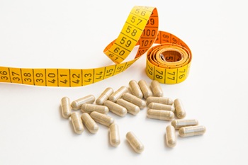 Capsules and a tape measure on a white background.