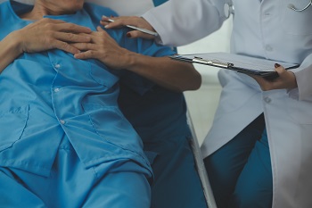 Patient lying in bed while doctor is doing intake and chart reporting. 